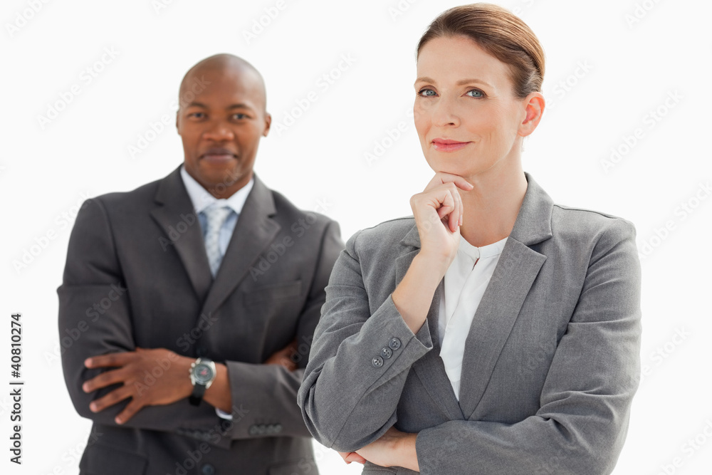 Smiling businessman behind businesswoman rests head on hand Smiling businessman behind businesswoman rests head on hand