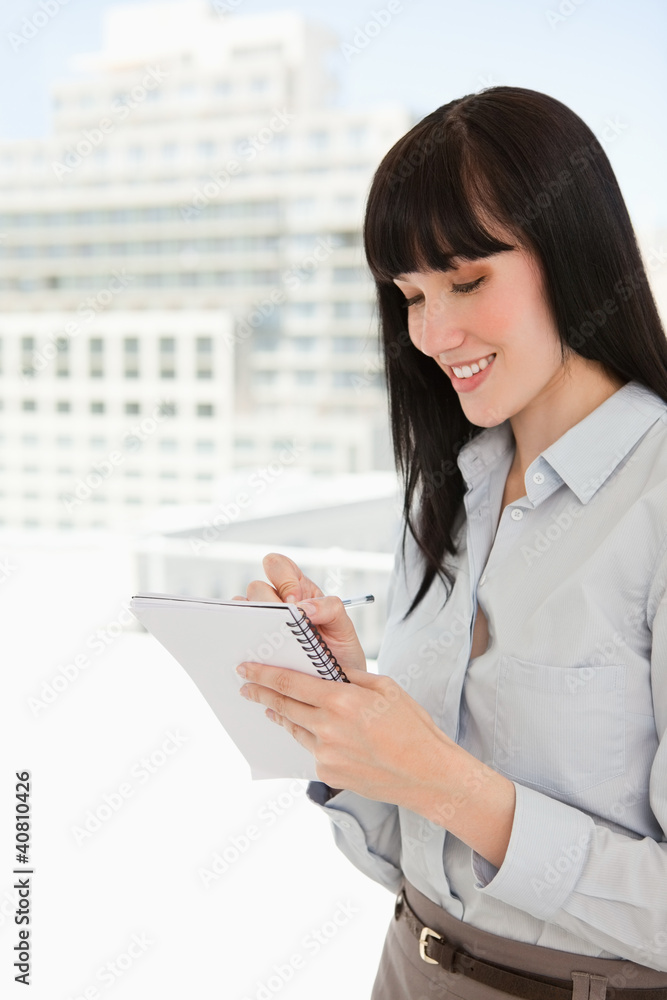 A smiling business woman writing down some notes A smiling business woman writing down some notes