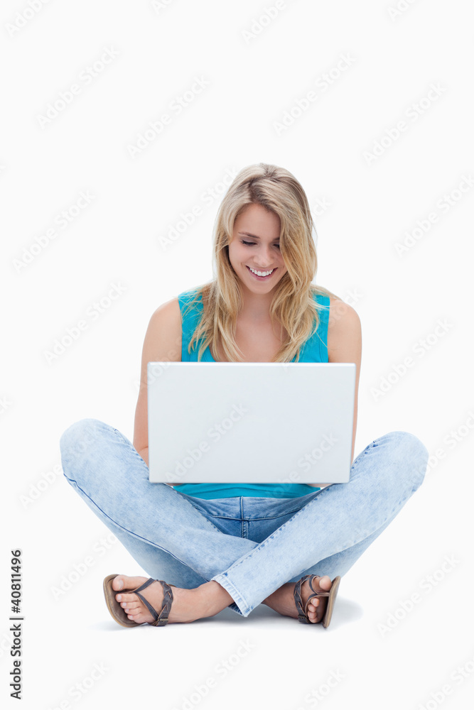A woman is sitting on the ground looking at her laptop A woman is sitting on the ground looking at her laptop
