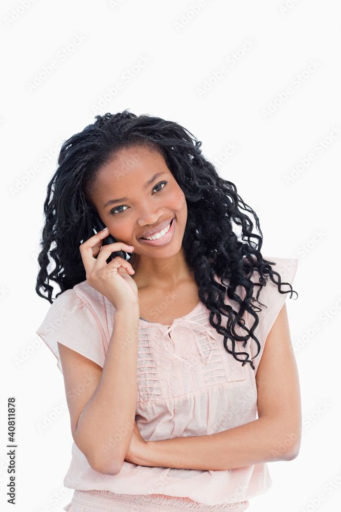 Fototapeta premium A young woman looking at the camera is talking on her mobile pho