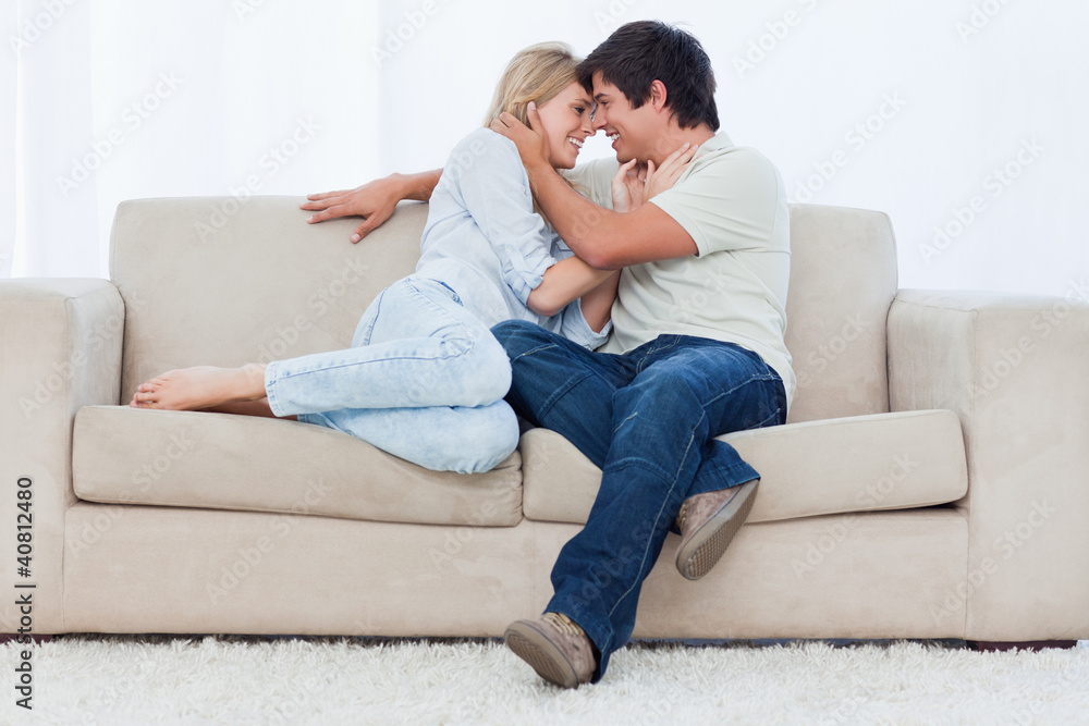 A couple are sitting on a couch looking at each other with their