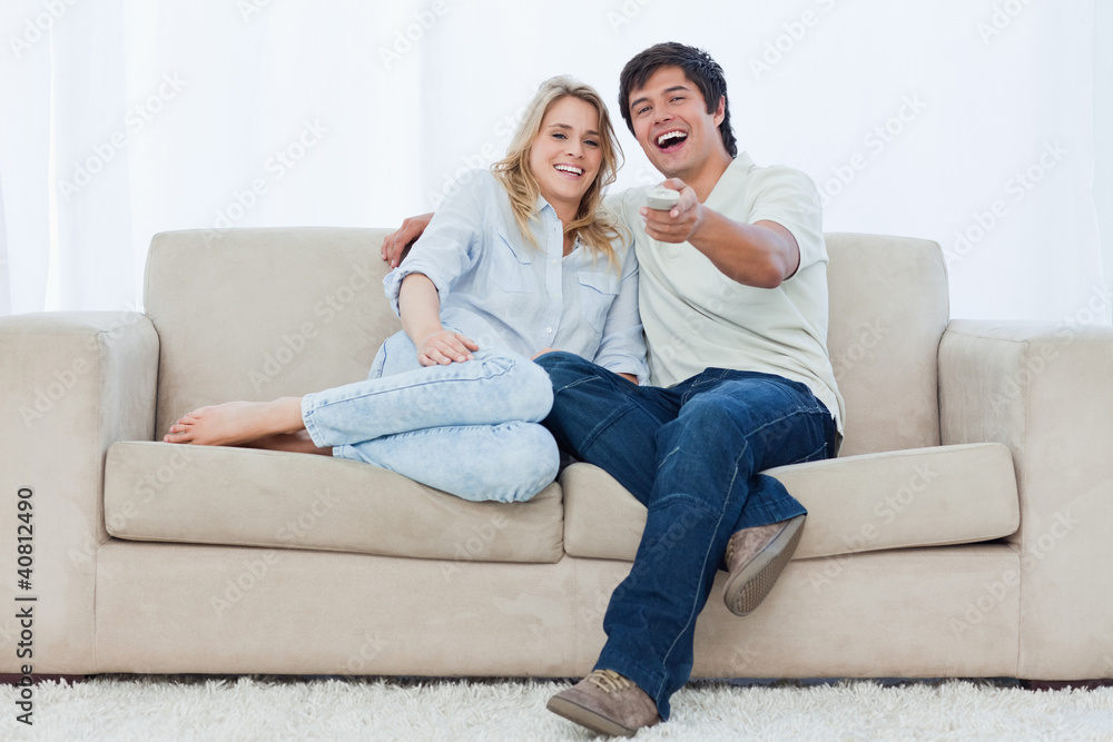 A young couple are sitting down looking at the camera and laughi A young couple are sitting down looking at the camera and laughi