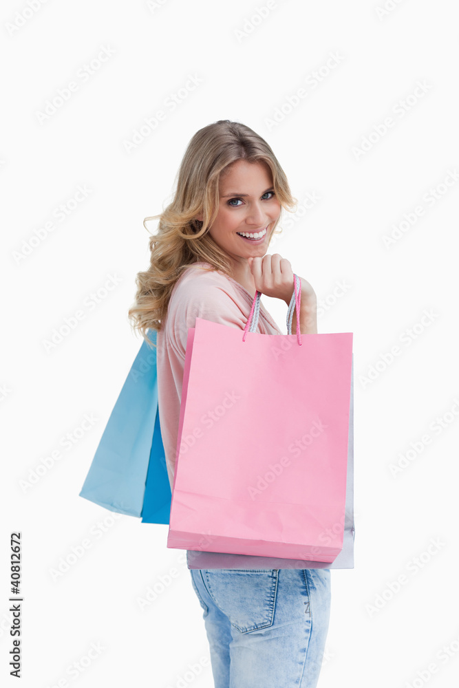 A woman carrying shopping bags is smiling at the camera