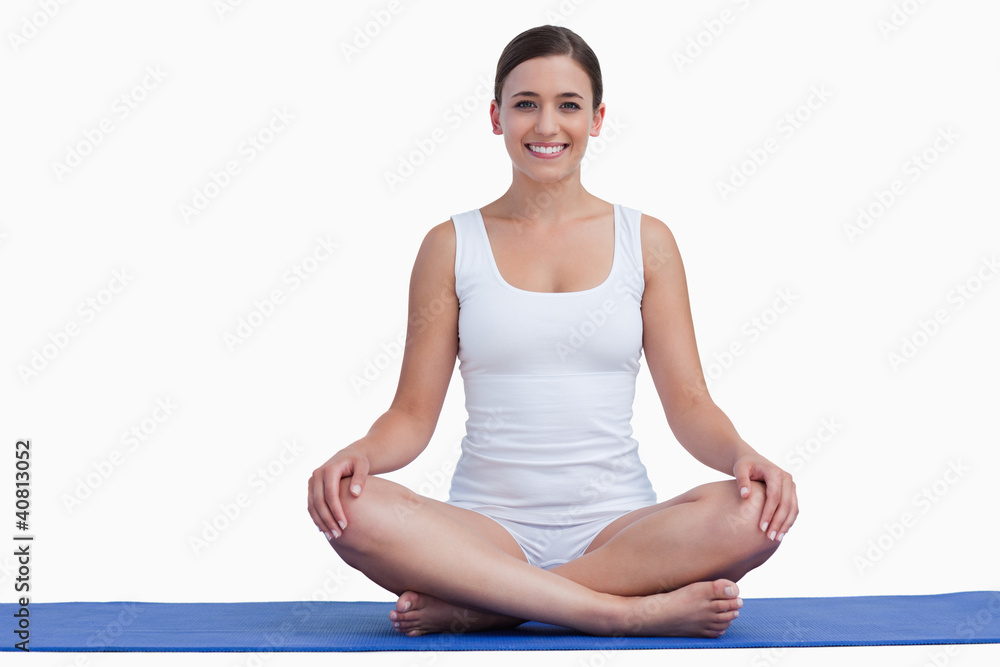 Smiling young woman meditating on a yoga mat Smiling young woman meditating on a yoga mat