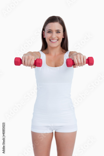 Red dumbbells being held by a young woman