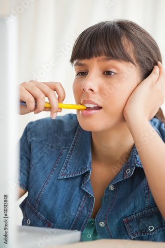 Fotografie Student grimacing while chewing a pencil