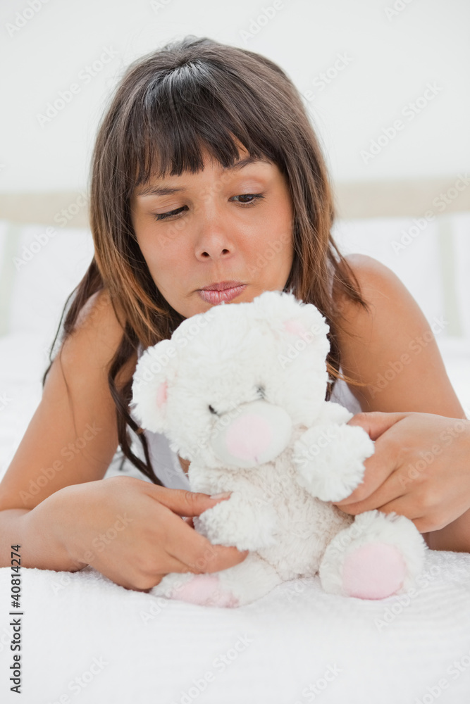 Grimacing young woman playing with a teddy bear