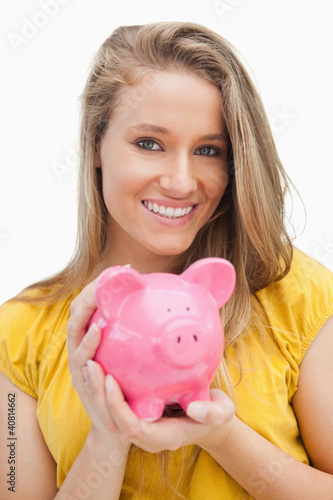 Portrait of a young blond woman holding a piggy-bank