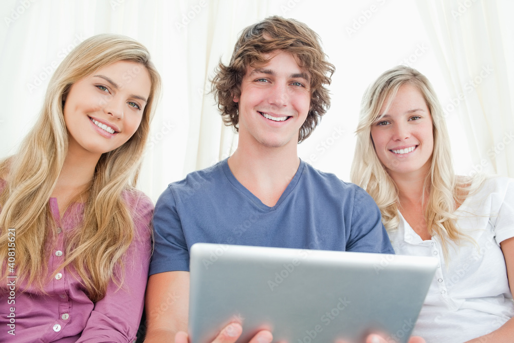 Three friends looking at the camera while holding a tablet Three friends looking at the camera while holding a tablet