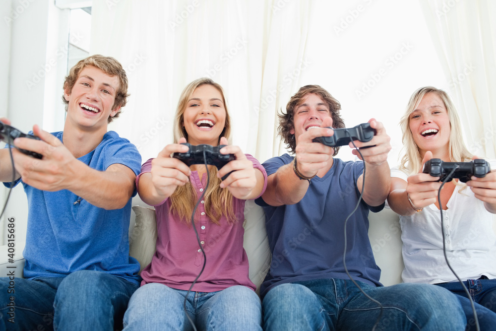 A group of friends all playing video games together and smiling A group of friends all playing video games together and smiling