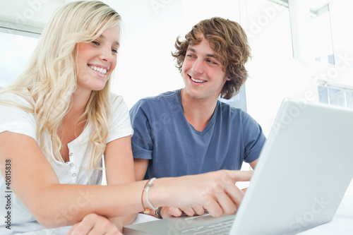 A couple use a laptop with a man looking at the woman