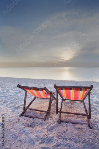 couples of wood teak chairs beacn and sun set scene photo