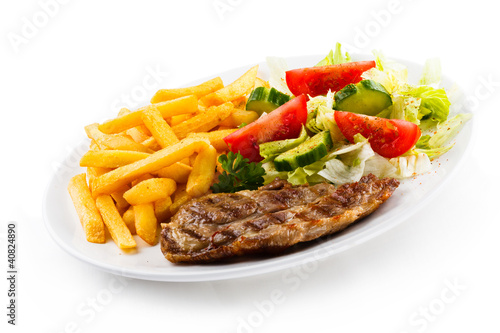 Grilled steaks, French fries and vegetables