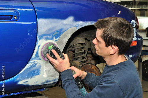 Car body worker sanding old paint..