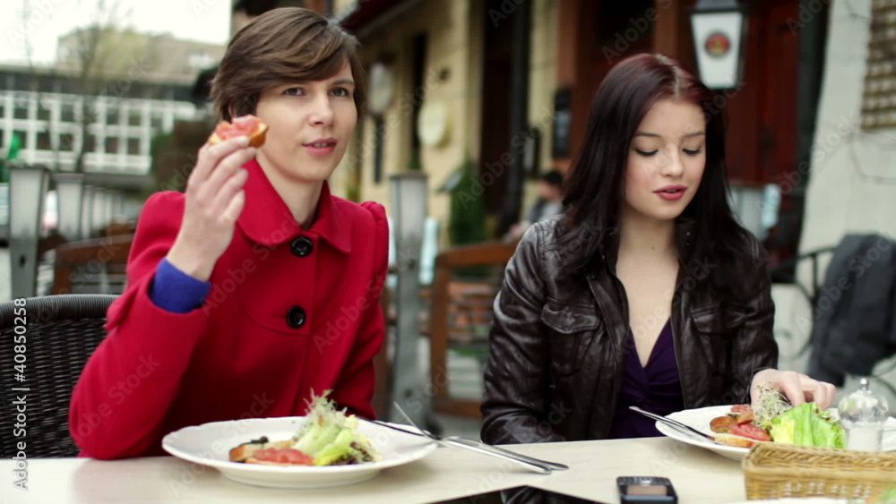 Two female friends talking and eating lunch in restaurant Two female friends talking and eating lunch in restaurant