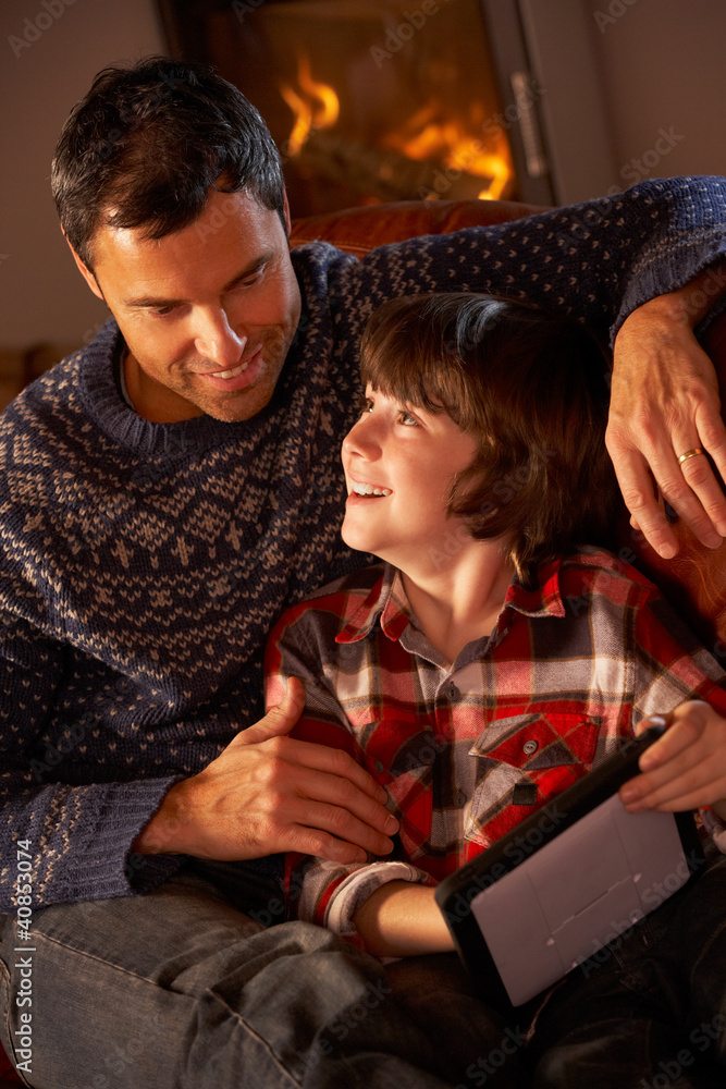 Father And Son Using Tablet Computer By Cosy Log Fire Father And Son Using Tablet Computer By Cosy Log Fire