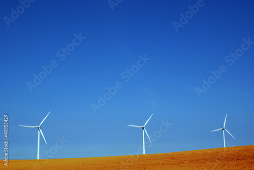 Three wind mills standing in red soil