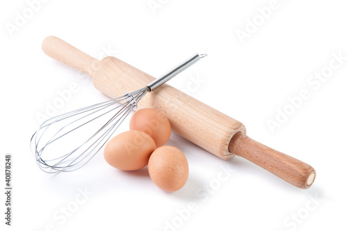 Brown eggs, rolling pin and wire whisk, isolated over white