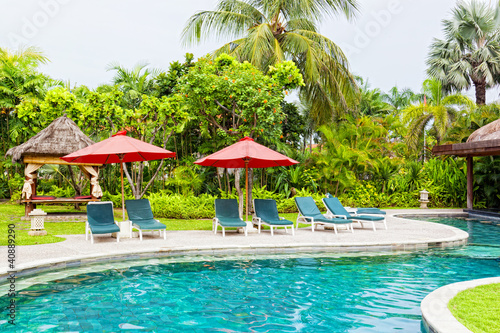 Chaise lounges at pool in hotel in tropics © Shchipkova Elena