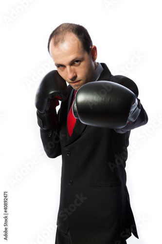 Businessman with boxing gloves in fighting stance punching