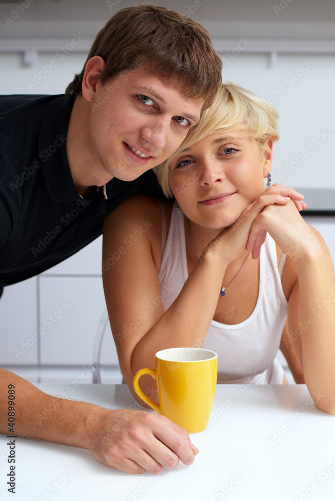 happy couple posing in the kitchen with cups happy couple posing in the kitchen with cups