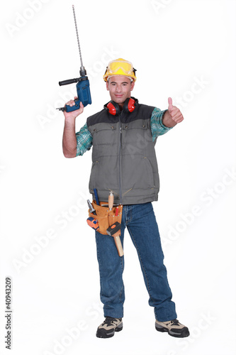 A handyman with a drill giving the thumb up.