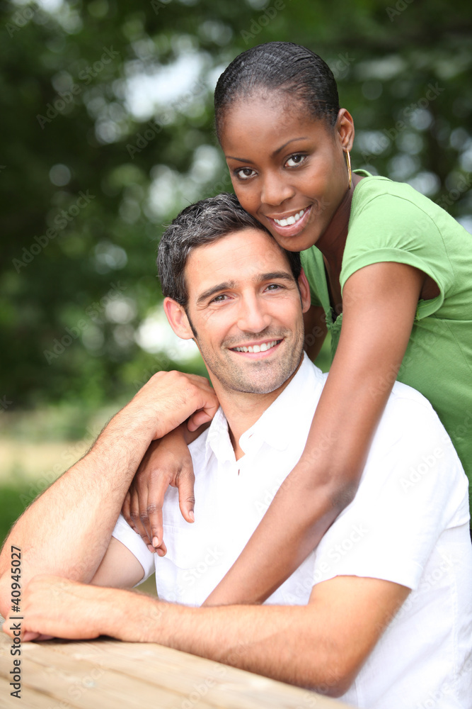 Mixed race couple sitting at a picnic table Mixed race couple sitting at a picnic table