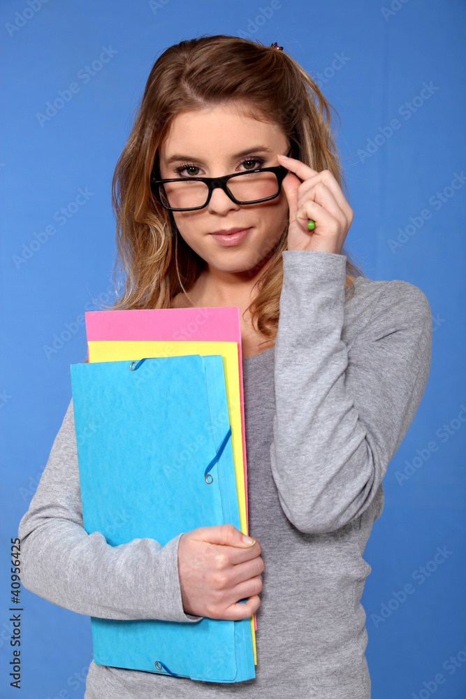 female student holding files against blue background female student holding files against blue background