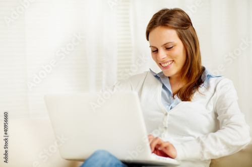Cute young woman smiling and working on laptop © pablocalvog