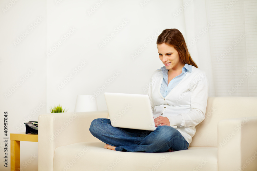 Caucasian woman working on sofa with a laptop Caucasian woman working on sofa with a laptop