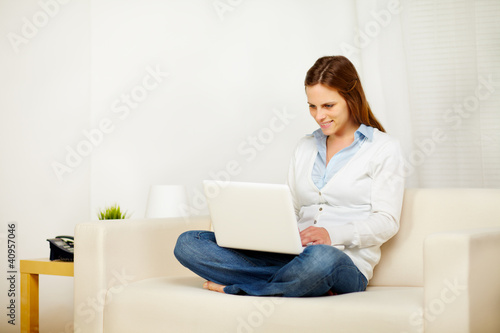 Caucasian woman working on sofa with a laptop