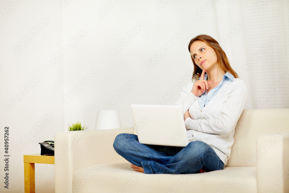 Young attractive woman thinking on sofa with a laptop Young attractive woman thinking on sofa with a laptop
