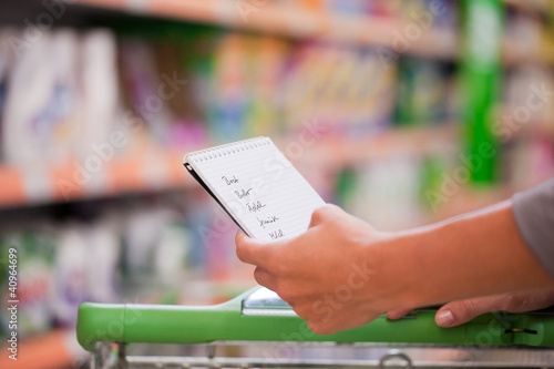 Junge Frau schiebt Einkaufswagen in Supermarkt photo