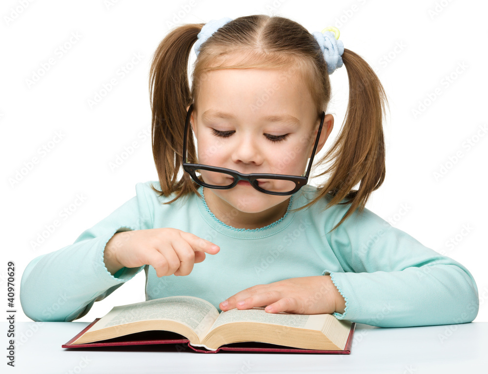 Cute little girl reads a book wearing glasses Cute little girl reads a book wearing glasses