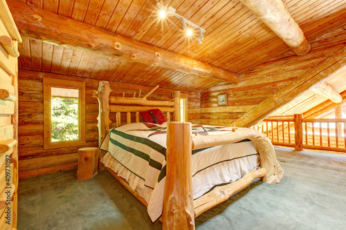 Log cabin bedroom under wood large ceiling.