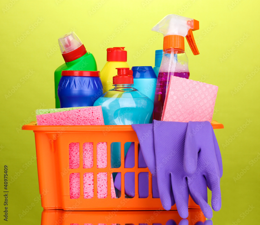 Basket with cleaning items on green background Basket with cleaning items on green background