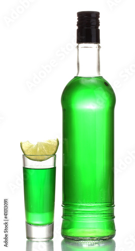 bottle and glass of absinthe with lime isolated on white