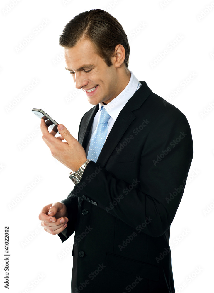 Male executive smiling as he reads message on his mobile Male executive smiling as he reads message on his mobile