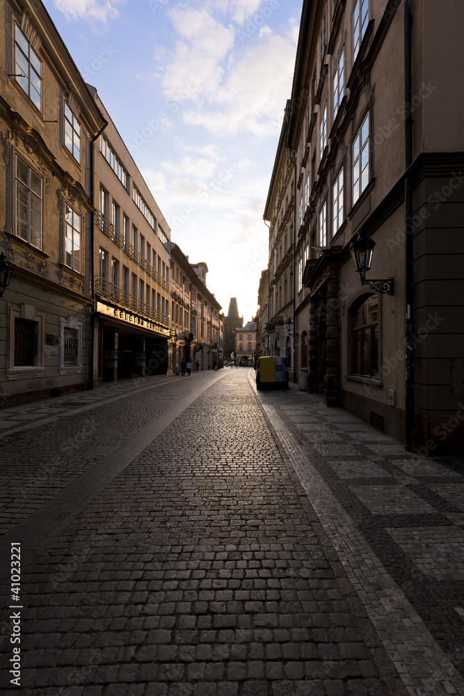 Dawns light reflects off  windows and stones on Prague street