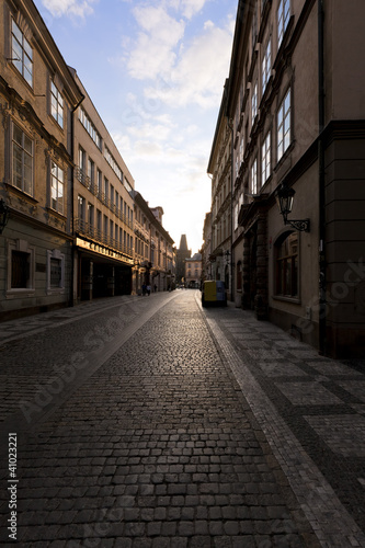Dawns light reflects off windows and stones on Prague street