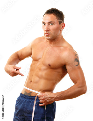 A muscular man measuring his waist