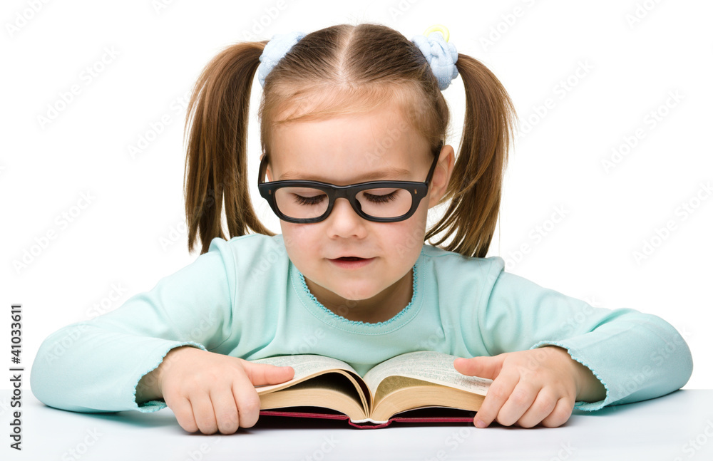 Cute little girl reads a book wearing glasses Cute little girl reads a book wearing glasses
