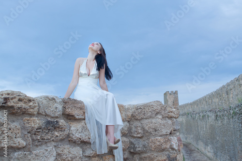 A young woman dressed in white against the sky