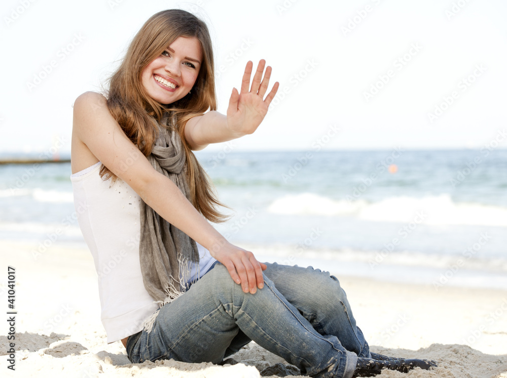 Funny teen girl sitting near the sea.