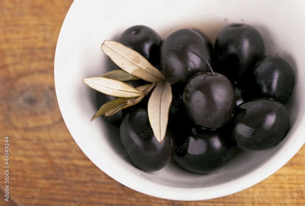 Olives on the wooden table on a white plate Olives on the wooden table on a white plate