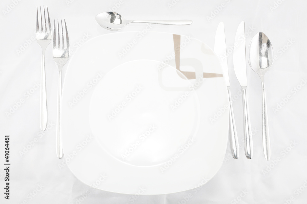 Plates with a silver fork, spoon, dessert spoon and a knife