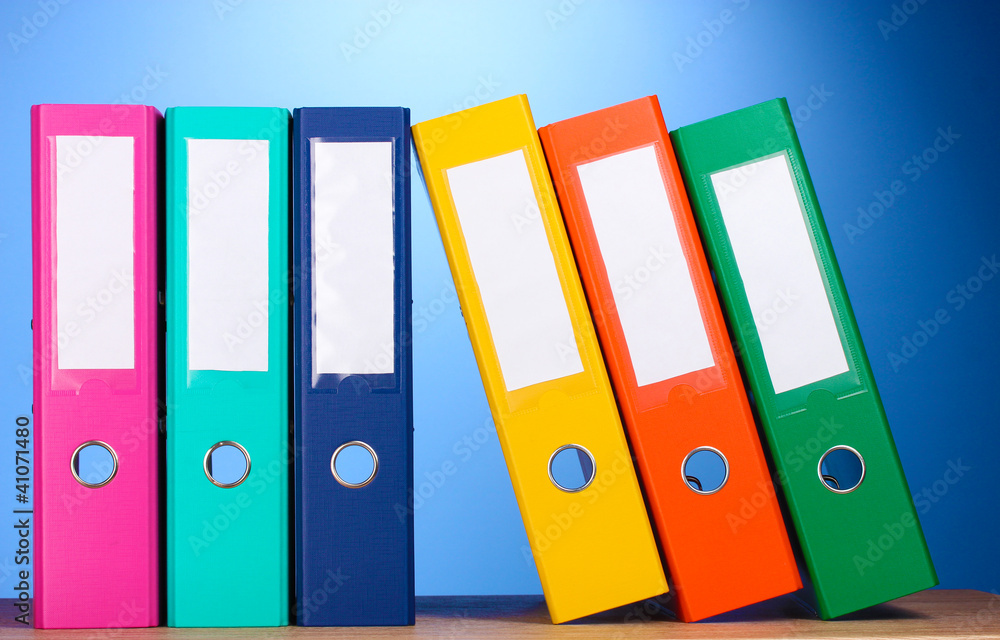 bright office folders on wooden table on blue background bright office folders on wooden table on blue background