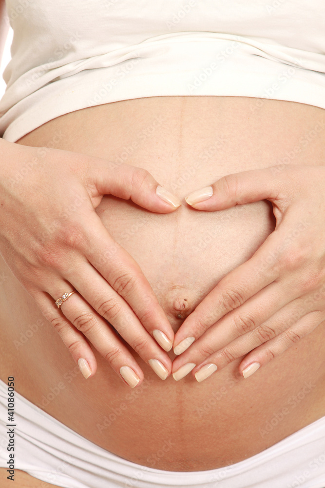 Closeup of a pregnant woman touching her belly with hands