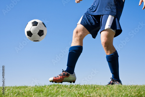 Fototapeta Naklejka Na Ścianę i Meble -  Soccer Player Kicking the ball - low angle