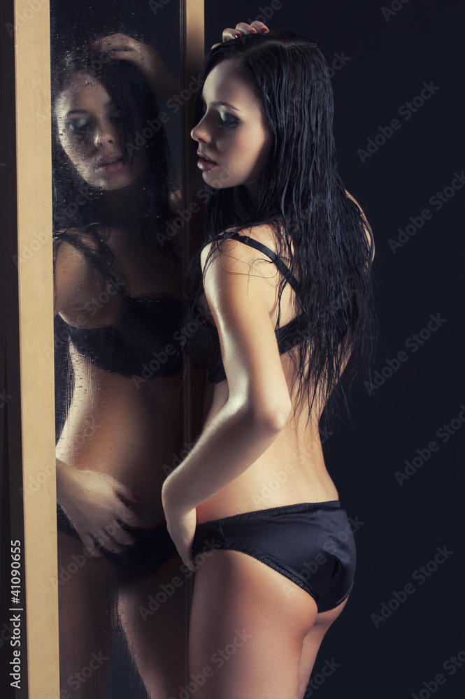 Foto de sexy woman in underwear standing next to a mirror do Stock
